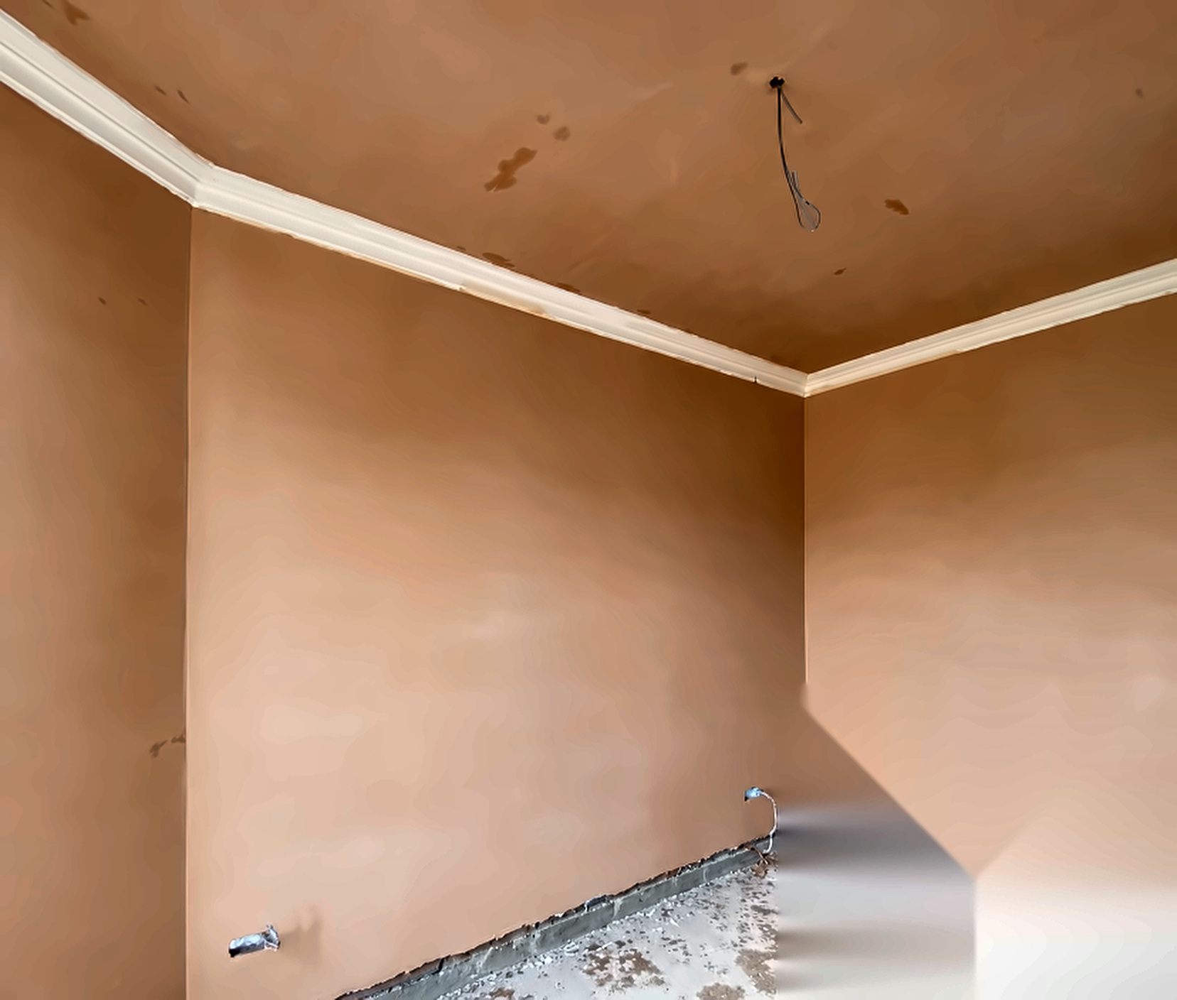 Close-up of wet plaster on corner walls beside white coving in a SE London home.